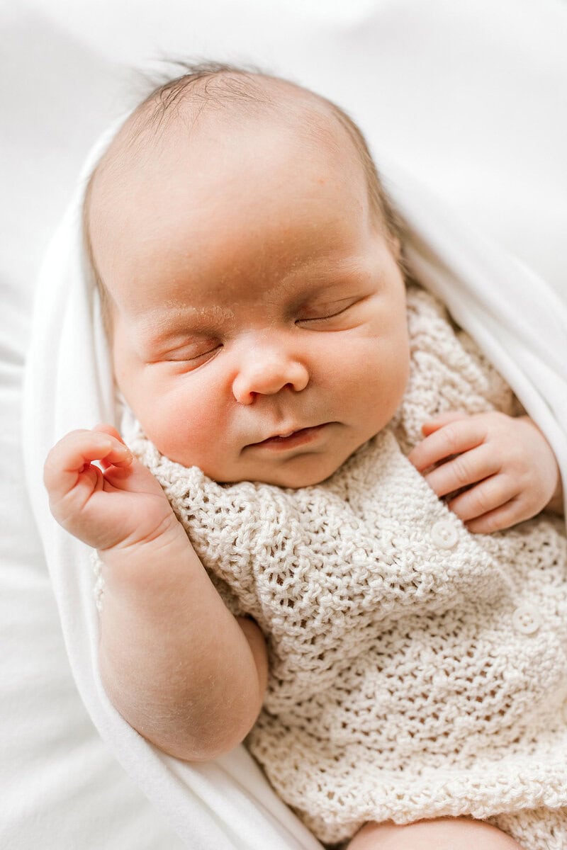 Adorable sleeping newborn baby wrapped in a knitted blanket.