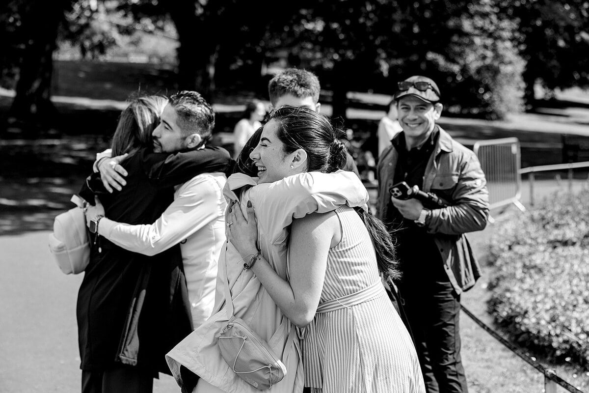Group of friends embracing in a park near Edinburgh Castle on a sunny day.
